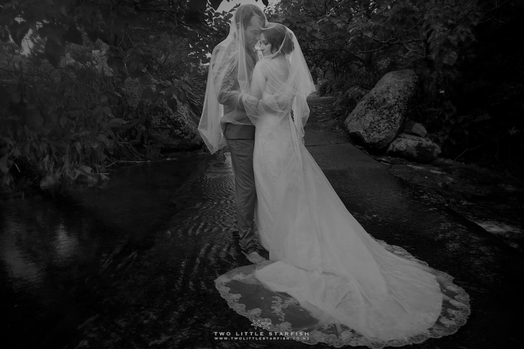 Bride and Groon standing in the water,showing the bride