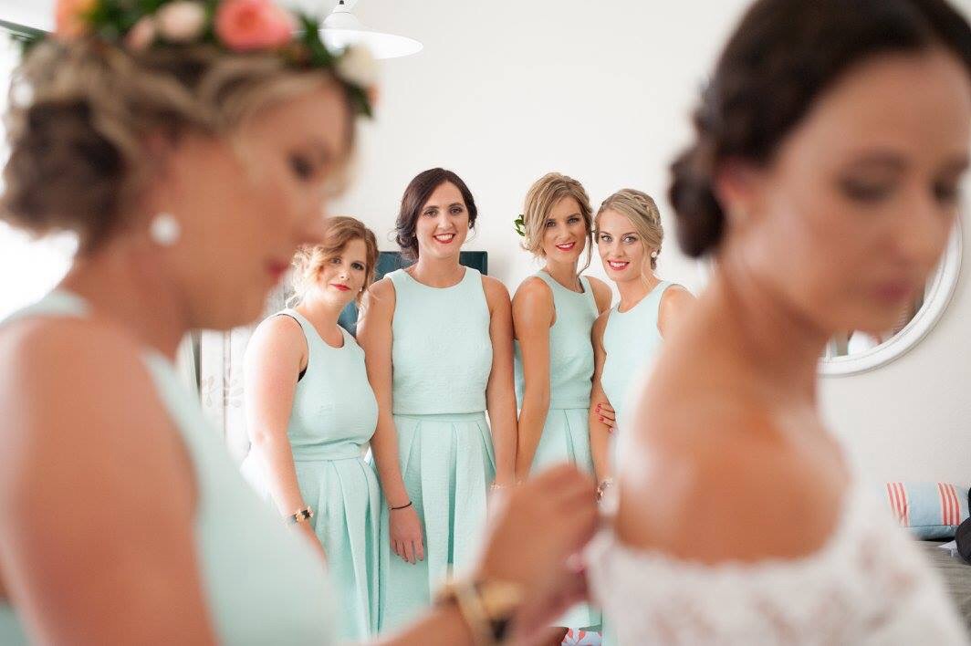 Bridesmaids looking on as bride being dressed u maid of honour. Hair laurel Stratford wedding hairstylist