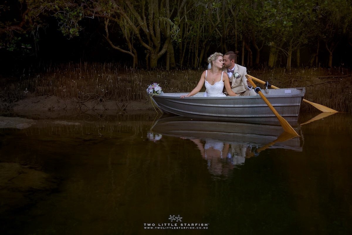 Bride and groom in small boat in river for creative shoot,russell NZ,wedding hair Laurel Stratford hairstylist