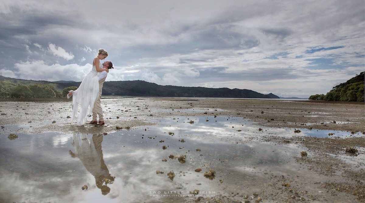 Bride and groom on beach with groom lifting bride,Russell ,NZ, wedding hair Laurel Stratford hairstylist