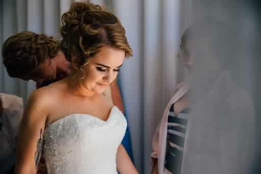 The bride getting her dress done up. Hair Laurel Stratford wedding hair
